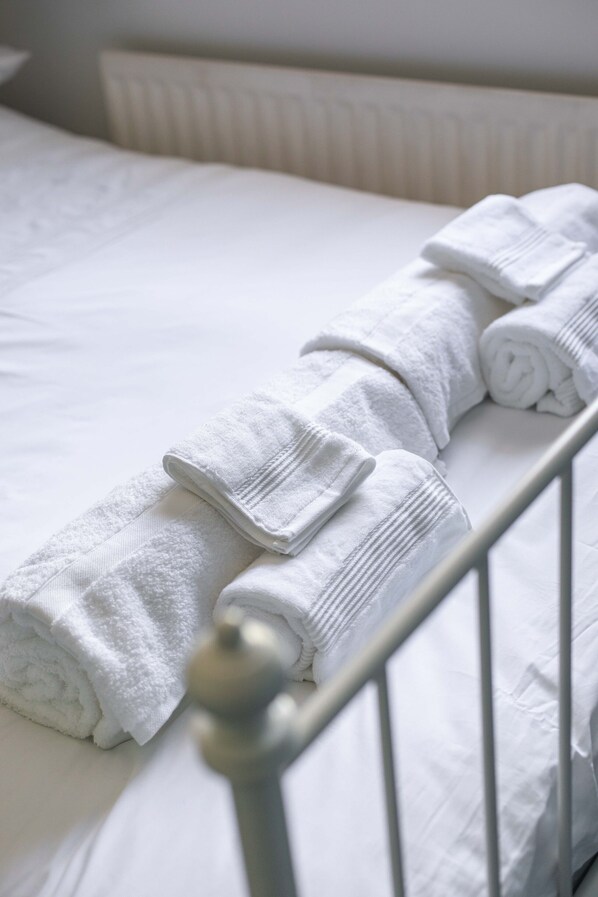 A neatly made bed with rolled white towels. - Fully Refurbished North Belfast Home (Belfast)