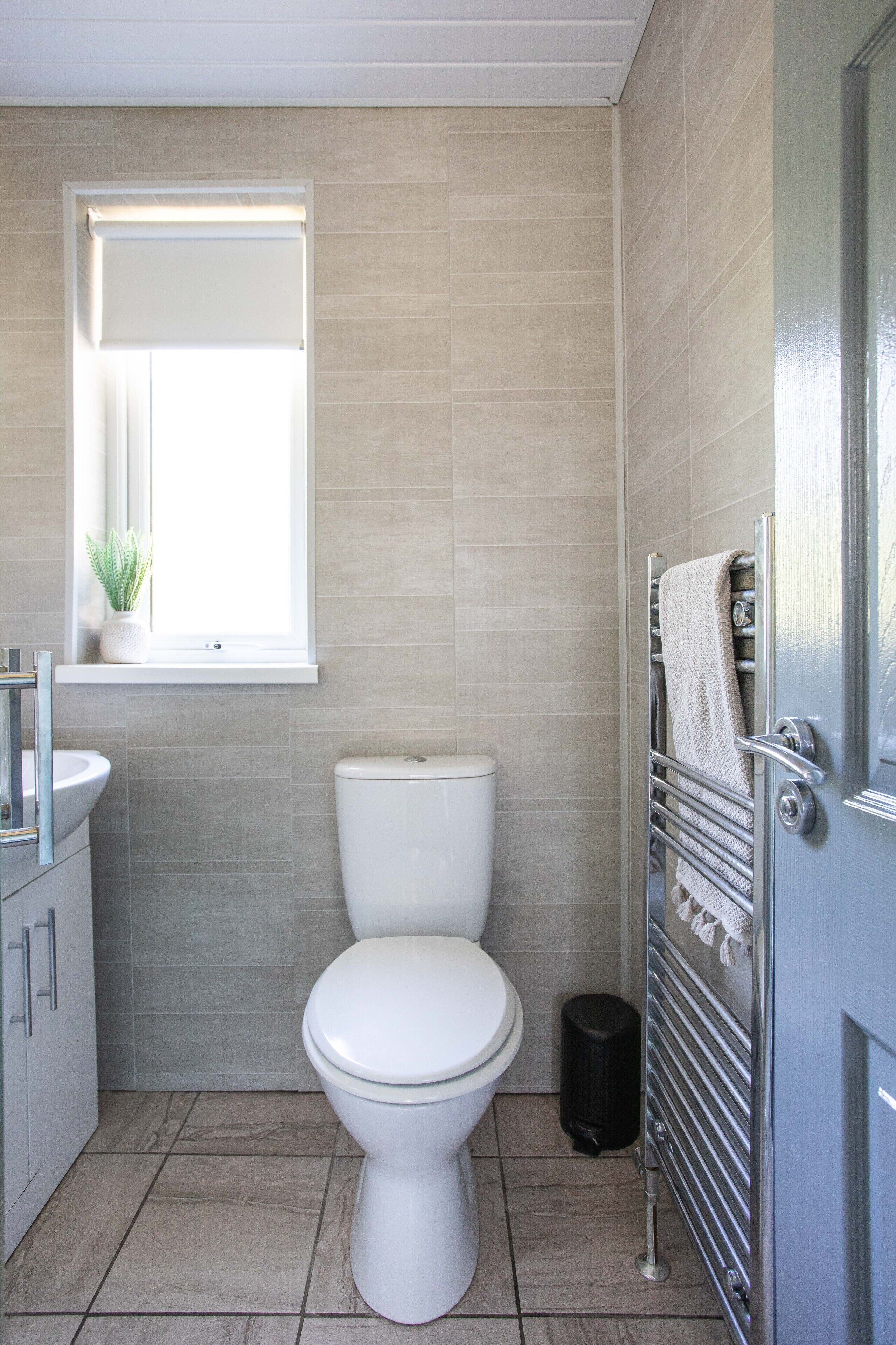 Un baño moderno con inodoro, lavamanos y ventana.