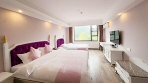 A hotel room with two beds, a TV, a desk, and a window with a view of greenery. - Milannuo Business Hotel (Xing'an County)