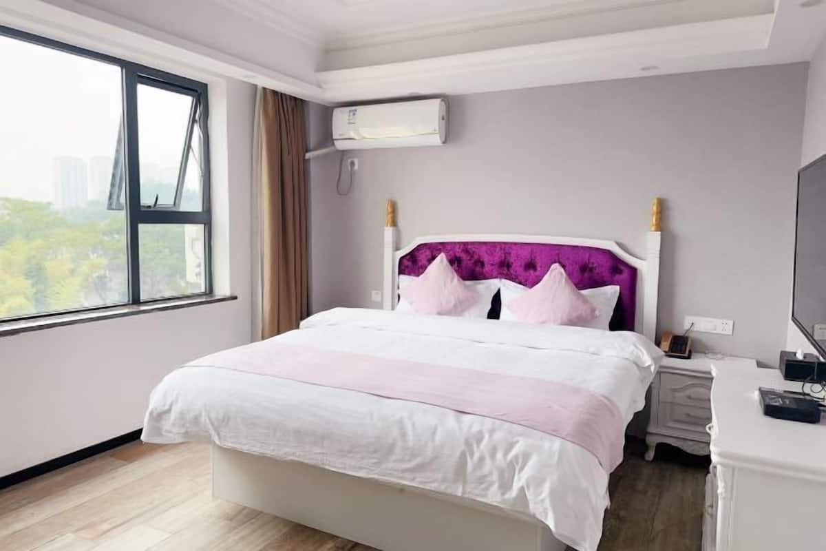 A bedroom with a bed, bedside table, and an air conditioning unit.