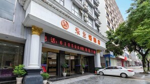 A hotel entrance with a large sign, columns, and a parked car. - Milannuo Business Hotel (Xing'an County)