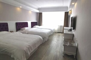 Quarto de hotel com duas camas, uma escrivaninha, televisão de tela plana e uma janela com cortinas.