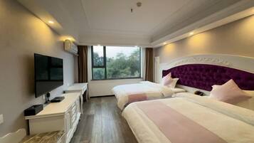 Une chambre d’hôtel avec deux lits, une télévision, un bureau et une fenêtre donnant sur des arbres.