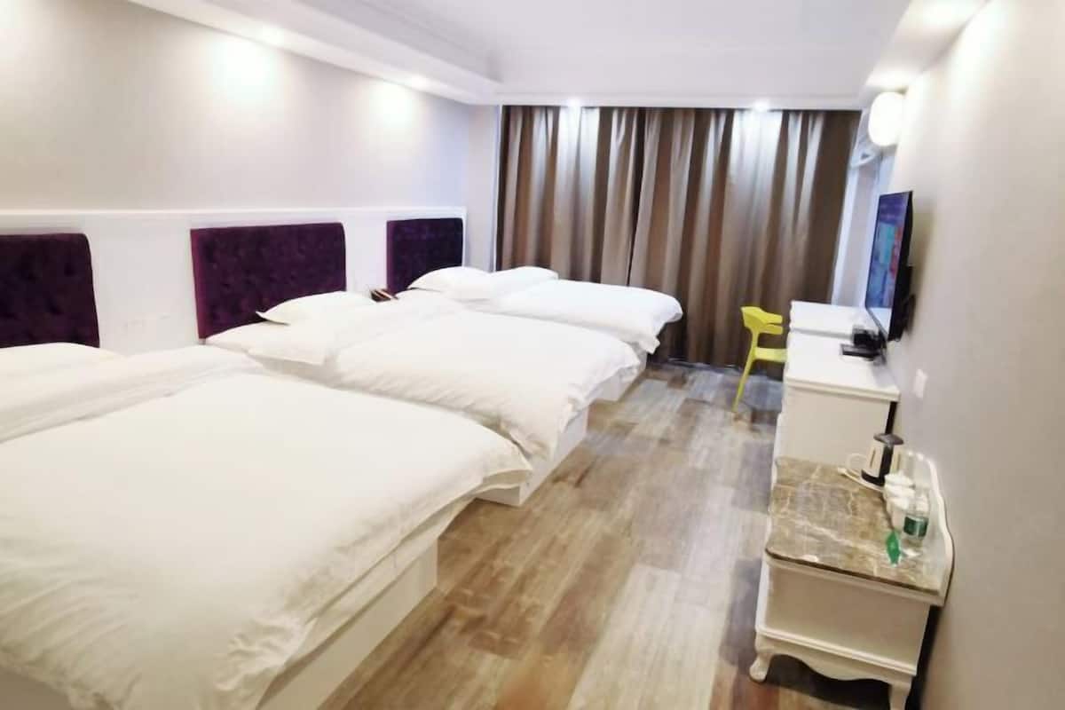 A hotel room with two beds, a desk, a chair, and a TV.