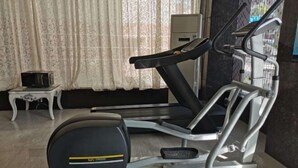 A home gym with a treadmill, a stationary bike, and a small table with a television. - Milannuo Business Hotel (Xing'an County)