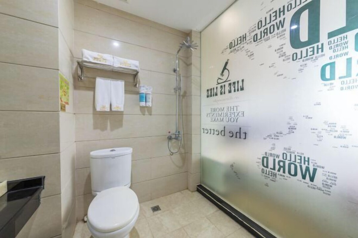 A bathroom with a toilet, a shower, and a glass wall with text.