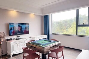 Ein Zimmer mit Fernseher, Billardtisch und Blick auf Bäume.