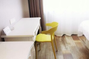 A hotel room with a bed, a small table, and a yellow chair.