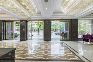 A spacious lobby with a patterned floor, large glass doors, and a purple sofa. - Milannuo Business Hotel (Xing'an County)