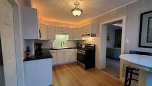 Een kleine keuken met witte kasten, een zwart aanrecht en een roestvrijstalen fornuis.