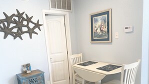 A dining area with a white table and chairs, a decorative star on the wall, and a framed picture of sailboats. - Third floor condo with ocean views  (Corpus Christi)