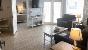 A modern living room with a flat-screen TV, a sofa, a coffee table, and a lamp. - Third floor condo with ocean views  (Corpus Christi)