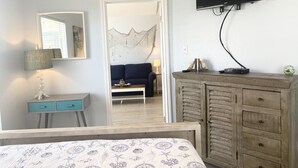 A bedroom with a bed, a dresser, a TV, and a sofa in the adjacent room. - Third floor condo with ocean views  (Corpus Christi)
