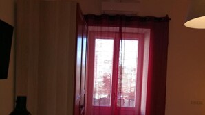 A room with a window covered by red curtains, a wall-mounted air conditioner, and a floor lamp. - B&B Antichi Riverberi in Station (Salerno)