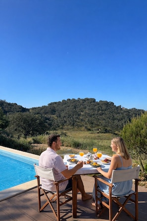 A dining table with a view of a swimming pool and a hill in the background. - Castro da Cola Field House (Ourique)