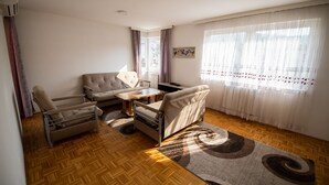 Ein Wohnzimmer mit einer Couch, zwei Sesseln, einem Couchtisch und einem gemusterten Teppich.