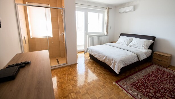 Ein Schlafzimmer mit einem Bett, einem Holztisch, einer Dusche und einem Fenster.