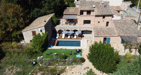 Una villa con piscina, zona de estar exterior y fachada de piedra.
