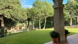 A covered patio area with a view of a well-maintained lawn and trees. - Villas Smeraldas Holiday In Sardinia (Sardegna)