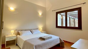 A bedroom with a bed, nightstands, a window, and a view of the outdoors. - Villas Smeraldas Holiday In Sardinia (Sardegna)