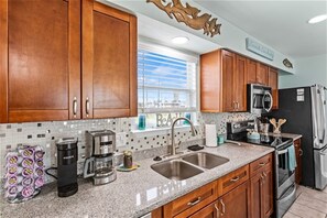 Fully equipped kitchen with stainless steel appliances, double sink, and refrigerator.