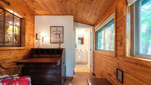 Een houten interieur met een bed, dressoir, lamp en een ingelijste foto aan de muur.