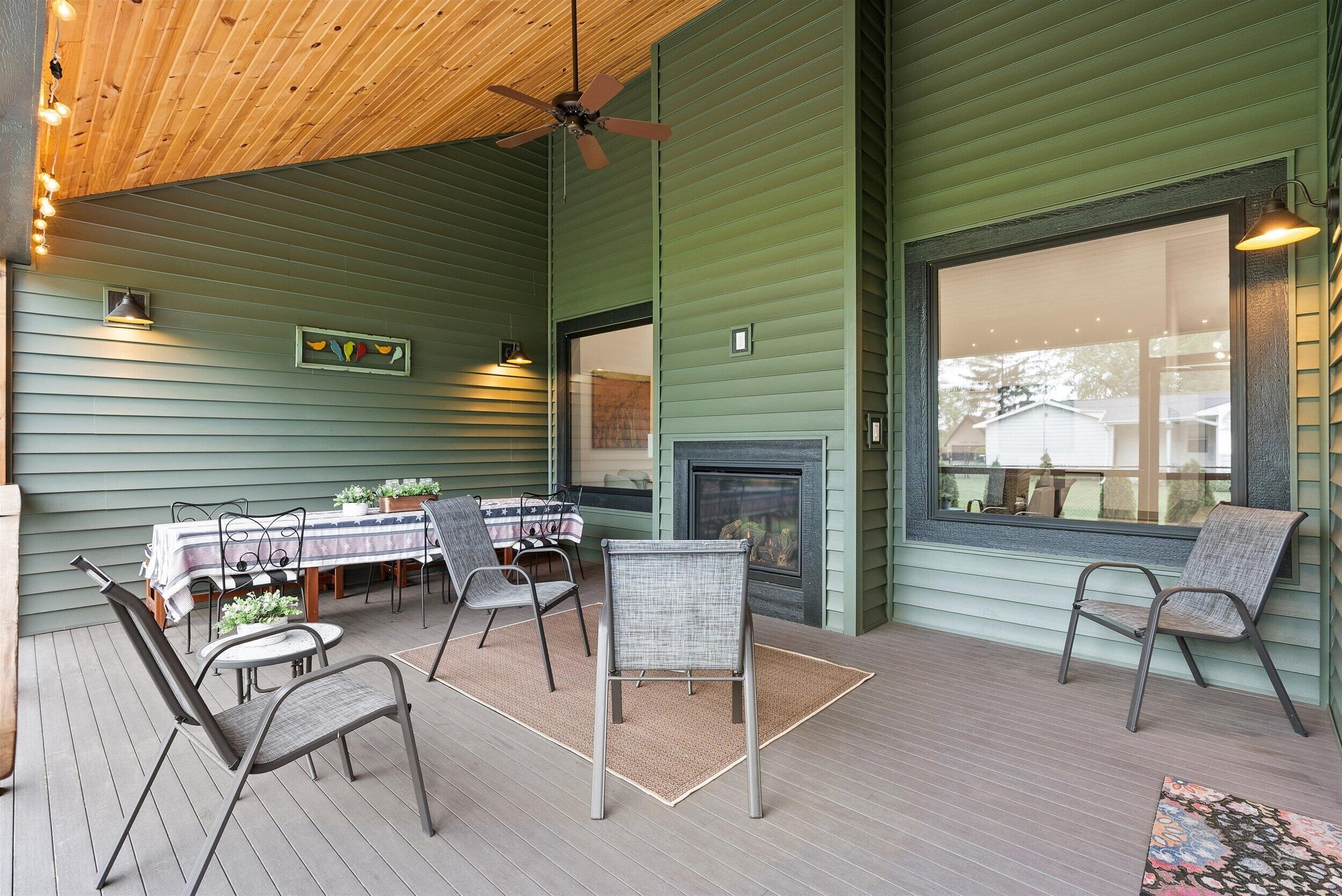 Un patio cubierto con techo de madera, paredes verdes, chimenea y mobiliario exterior.