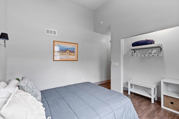 A bedroom with a bed, a framed picture, a shelf with clothes, and a bench. - 4Bed 3.5Ba Cozy New Construction! Close to Lake Geneva and Lake Elizabeth! (Twin Lakes)