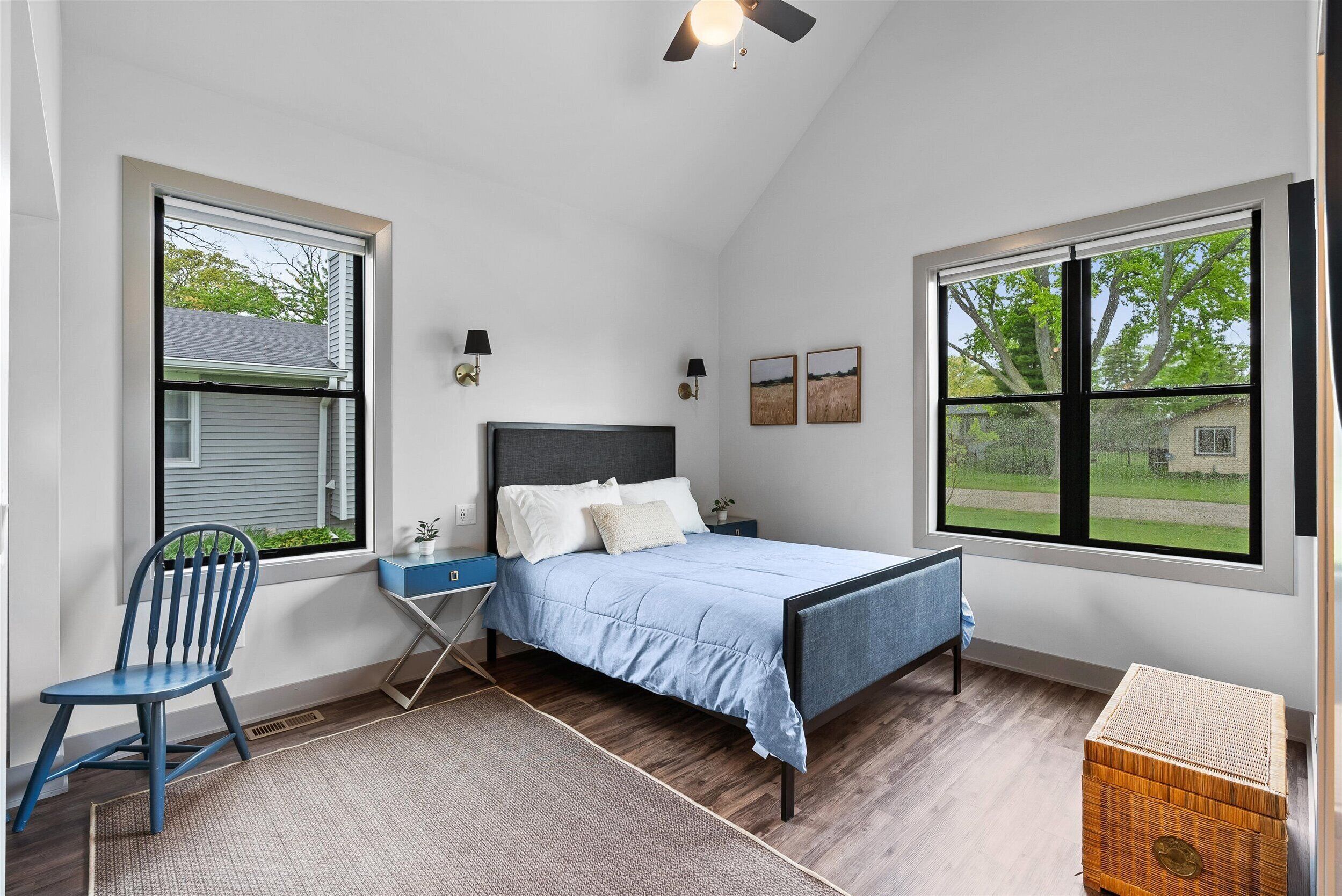 Een slaapkamer met een bed, een stoel, een nachtkastje en een raam.