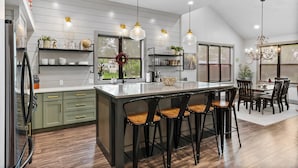 Een moderne keuken met een groot kookeiland, barkrukken en hanglampen.