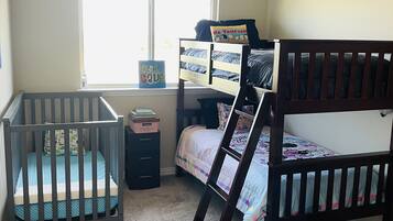 Ein Kinderzimmer mit Etagenbetten, einem Babybett, einem Fenster und einem Star Wars Poster.
