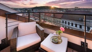 A balcony with wicker furniture and a table with a vase and glass.