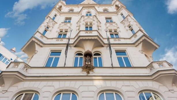A multi-story building with a symmetrical facade, large windows, and a central decorative element.