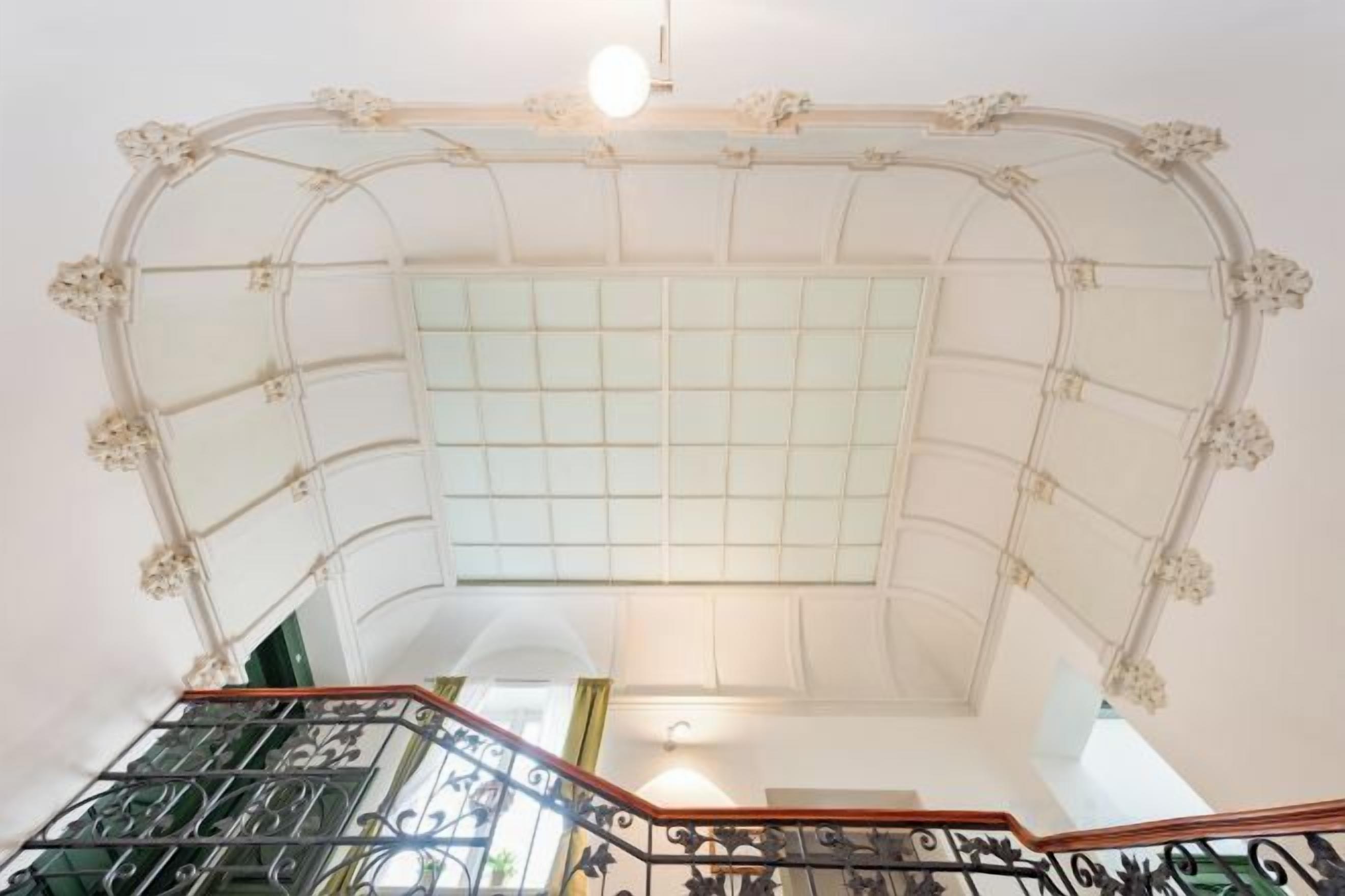 A grand staircase with ornate railings and a glass ceiling.
