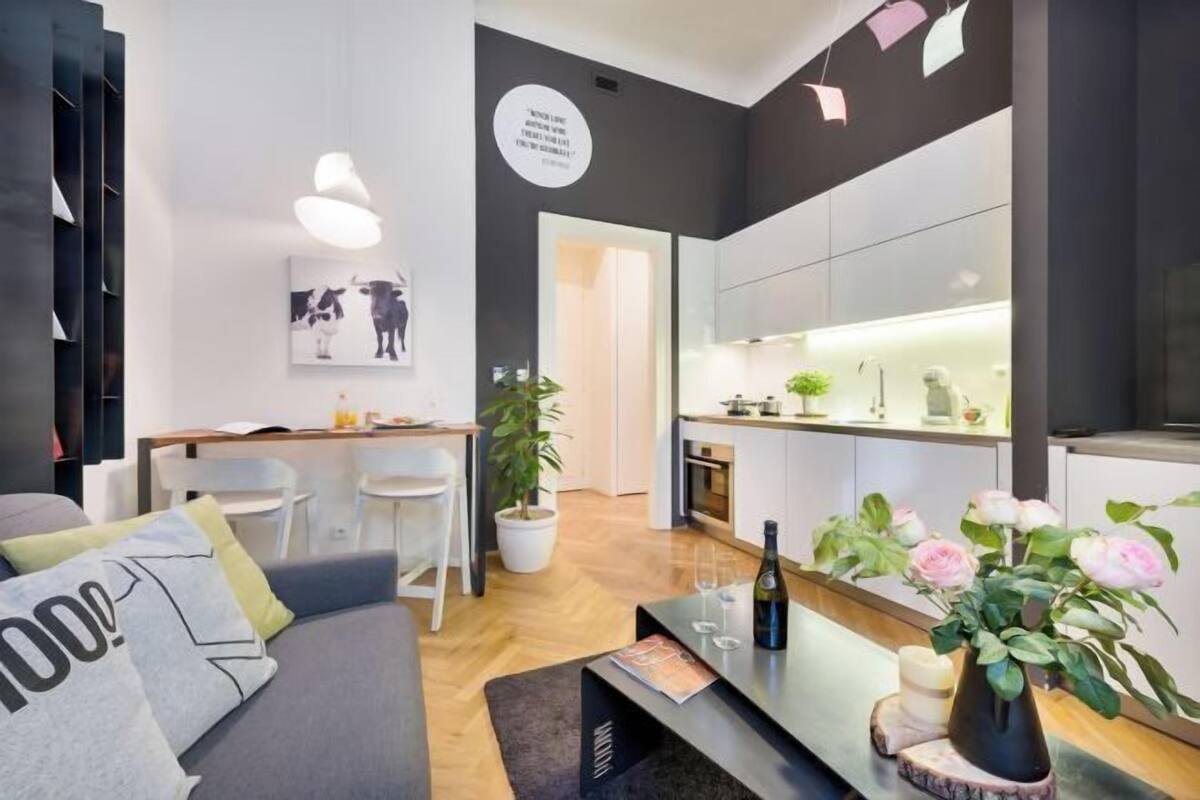 A modern living room with a sofa, a coffee table, a dining area, and a kitchen.