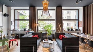 A modern office space with two black sofas, a round coffee table, and a large window with a view of buildings.