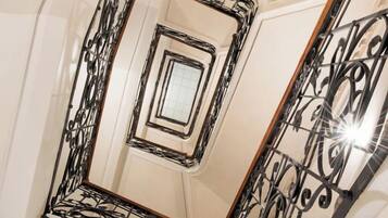 Un escalier en colimaçon orné de rampes en métal ouvragé et d’un mur recouvert de miroirs.