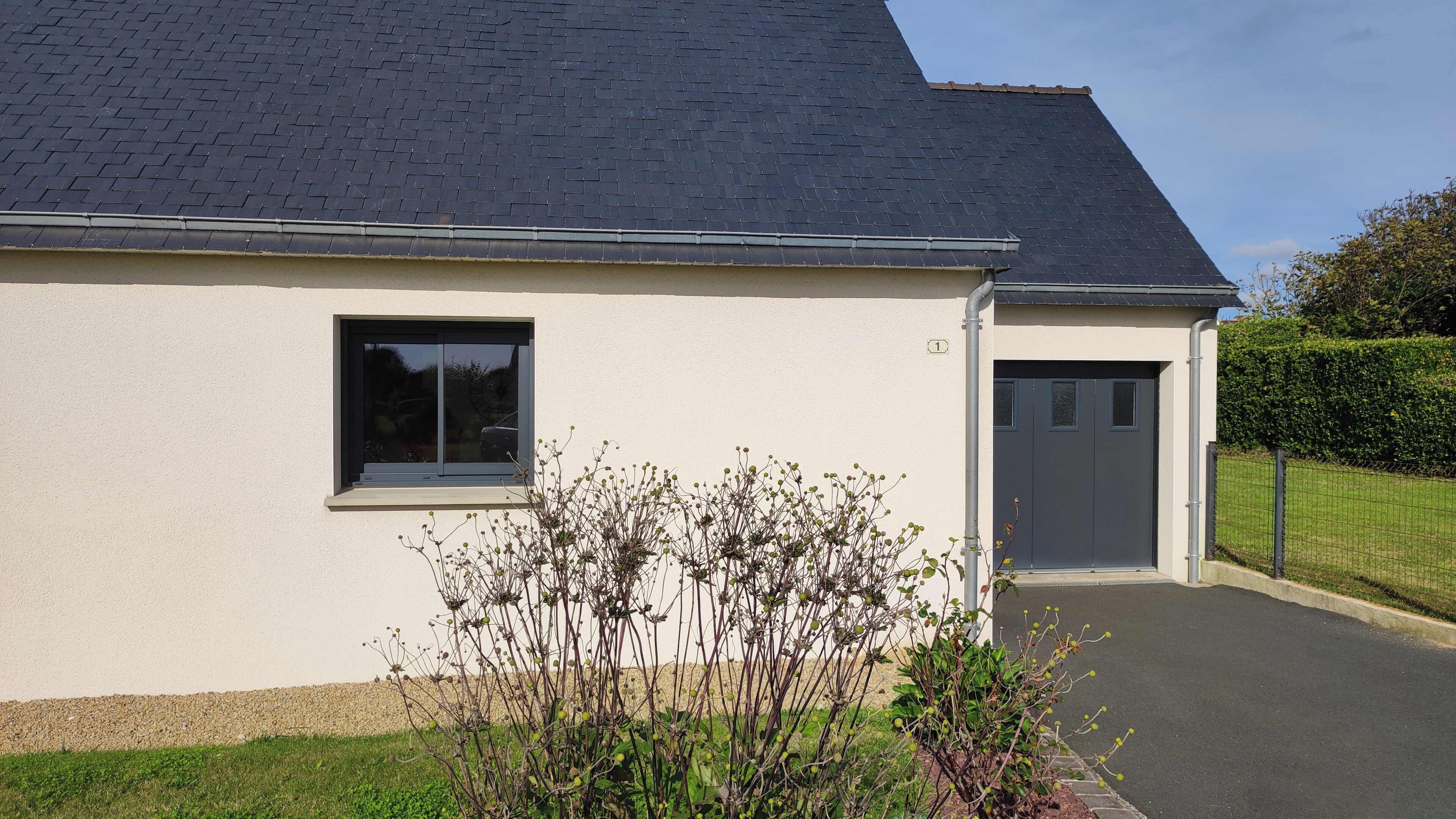 A single-story building with a dark roof, a window, and a door.