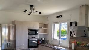 Une cuisine moderne avec des meubles en bois clair, des appareils électroménagers en acier inoxydable et un îlot central.