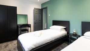A bedroom with a bed, a desk, and a wardrobe.