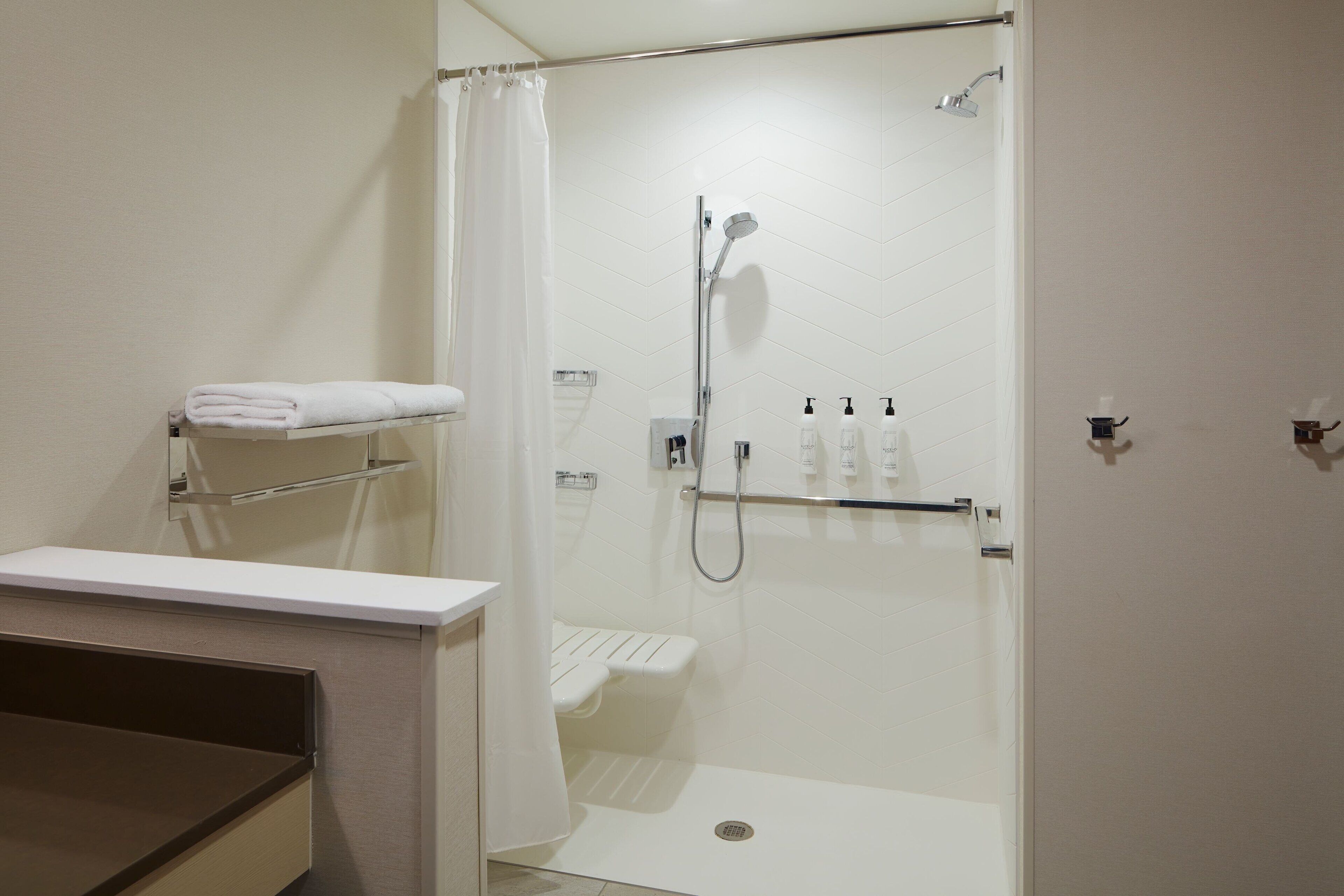 A modern bathroom with a shower, toilet, and a towel rack.