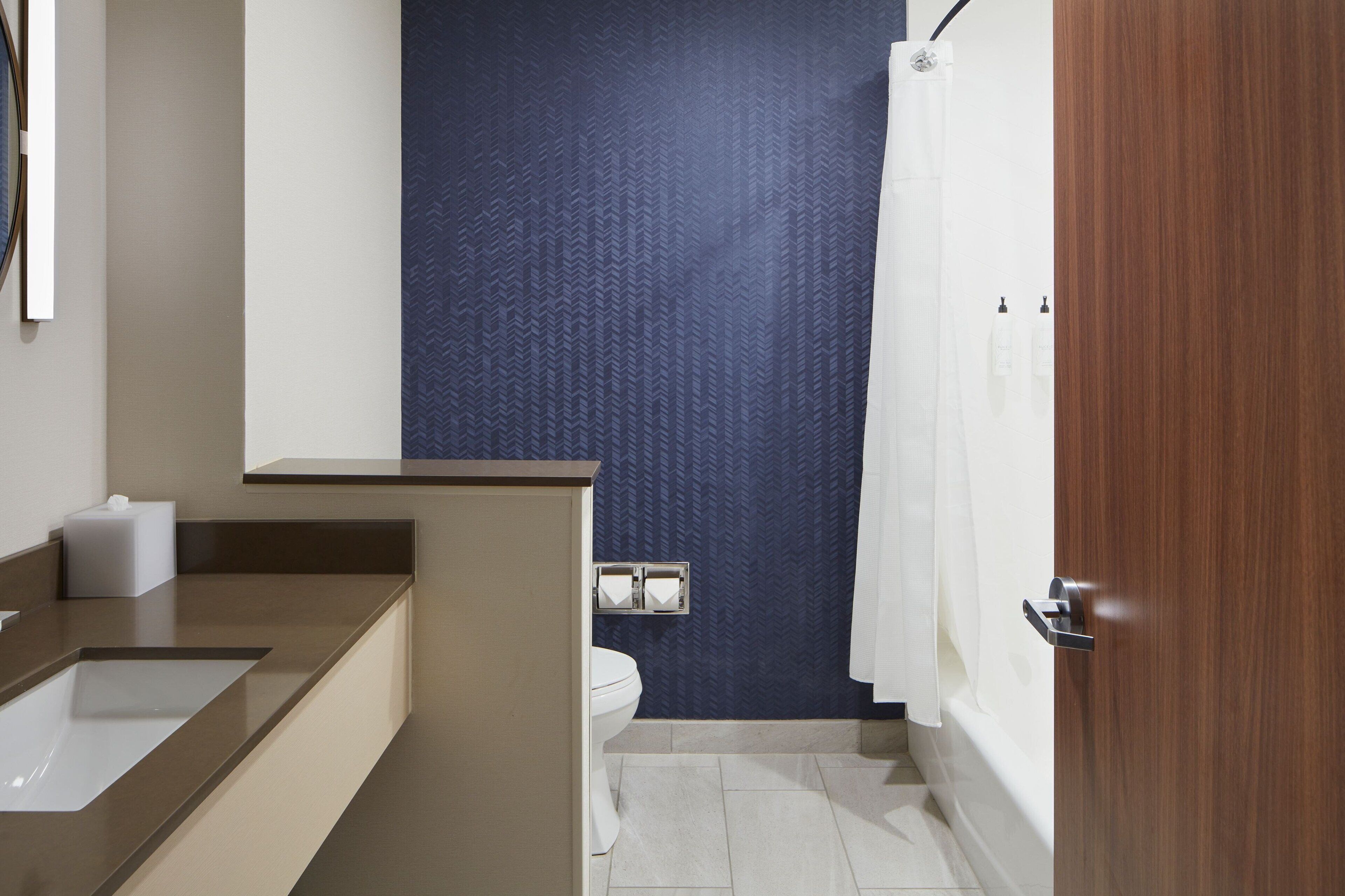 Un baño moderno con lavamanos, inodoro y zona de ducha.