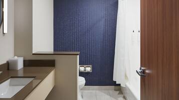 Un baño moderno con lavamanos, inodoro y zona de ducha.