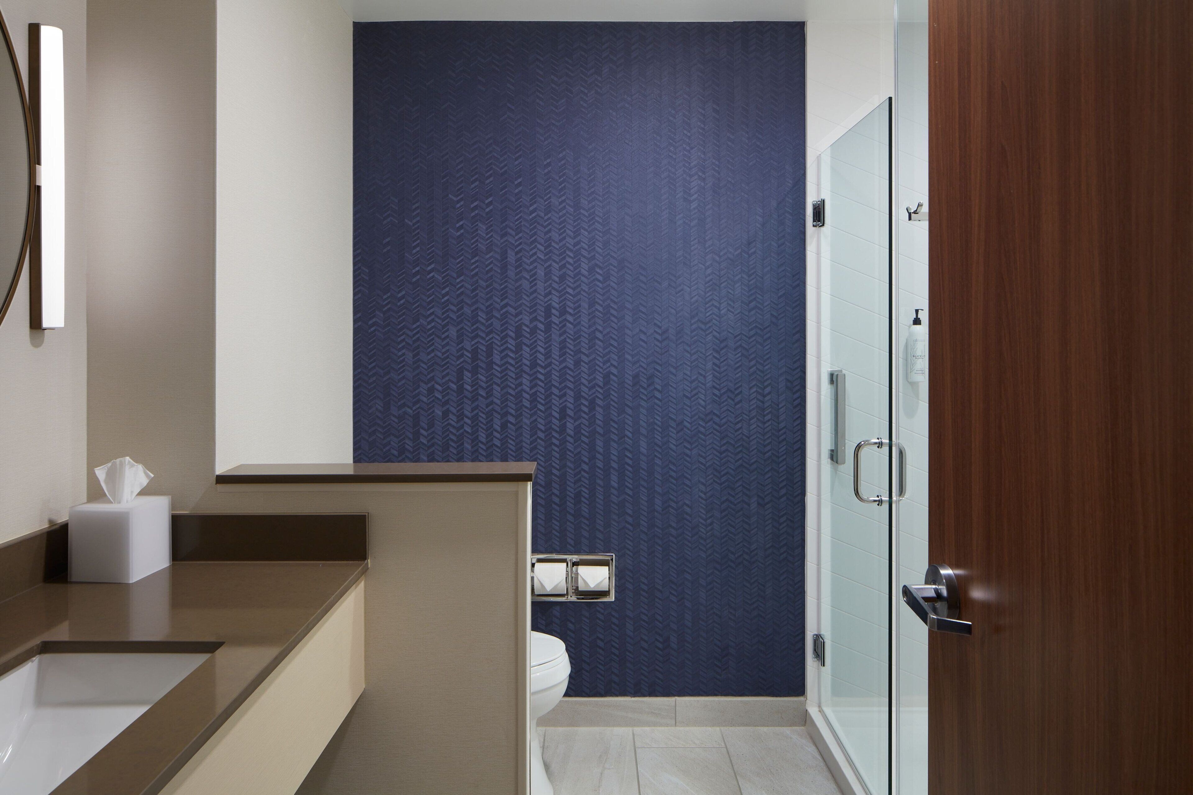 A modern bathroom with a large mirror, a toilet, and a shower area.