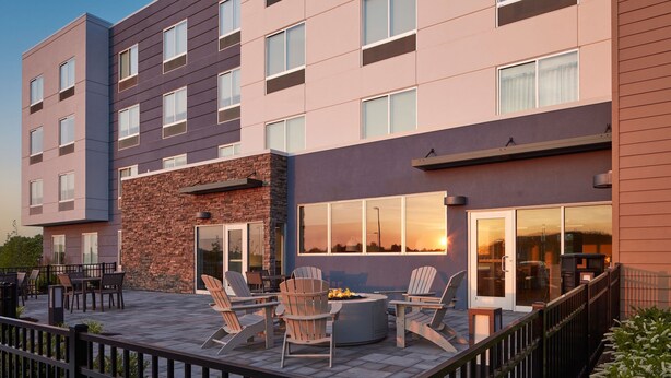 A modern building with a patio area featuring outdoor seating and a fire pit. - Fairfield Inn & Suites by Marriott Middletown (Middletown)