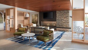 A modern living room with a stone fireplace, wooden ceiling, and a large TV mounted above it. - Fairfield Inn & Suites by Marriott Middletown (Middletown)