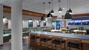 A modern restaurant with a long counter, multiple seating areas, and pendant lighting. - Fairfield Inn & Suites by Marriott Middletown (Middletown)