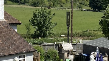 A rural house with a white exterior, a sloped roof, and a fenced yard.