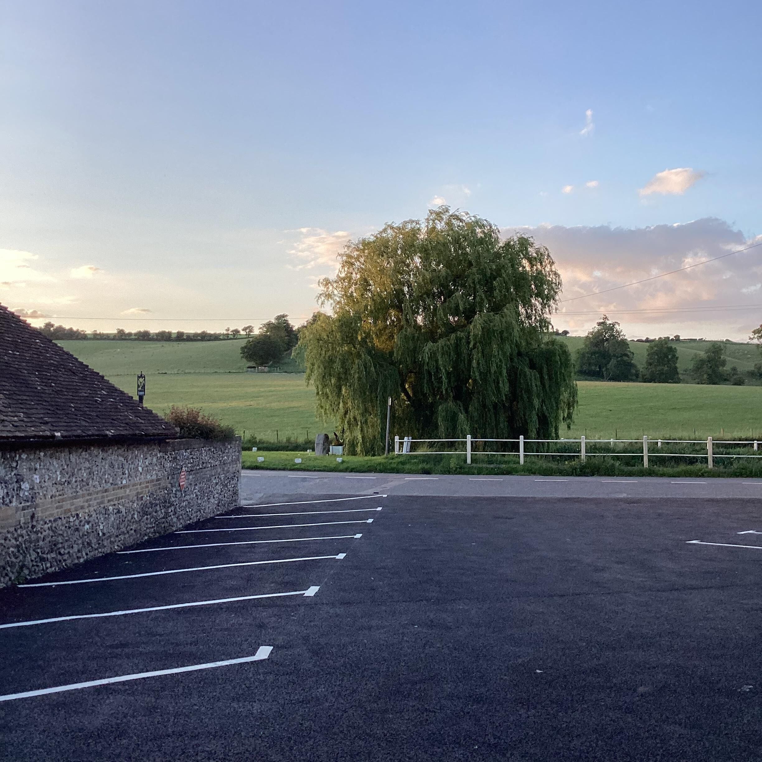 A parking lot with a stone wall and a tree in the background.