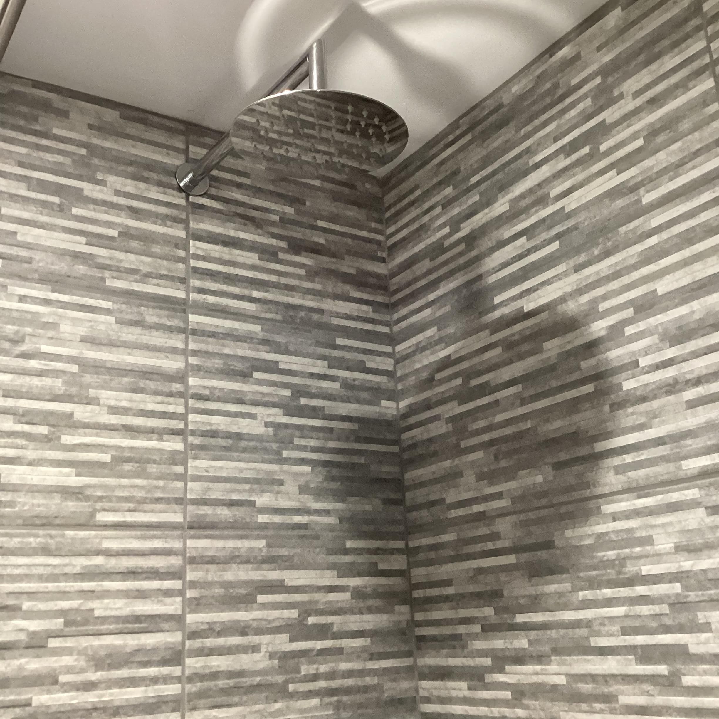 Um chuveiro com design moderno e textura na parede.